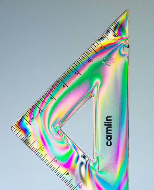 A triangular ruler with rainbow colors and markings.